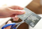 Female hands cutting credit card with scissors