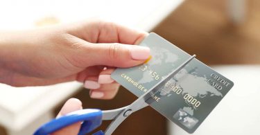 Female hands cutting credit card with scissors