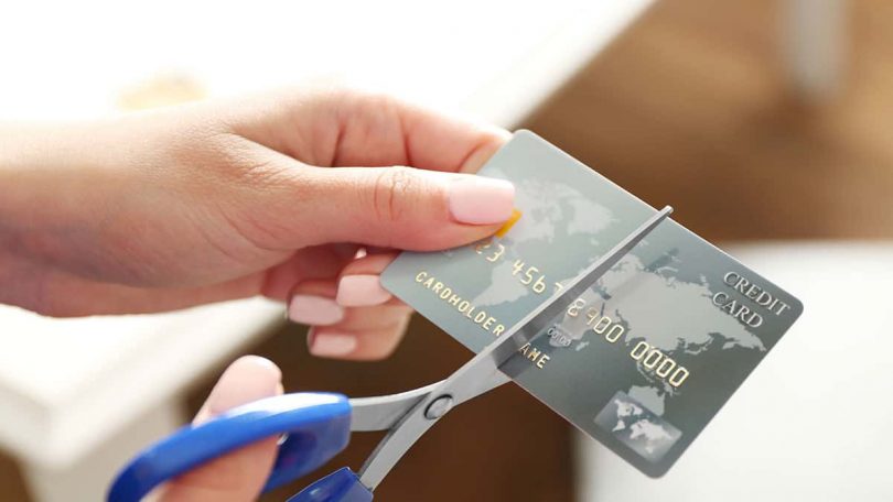 Female hands cutting credit card with scissors