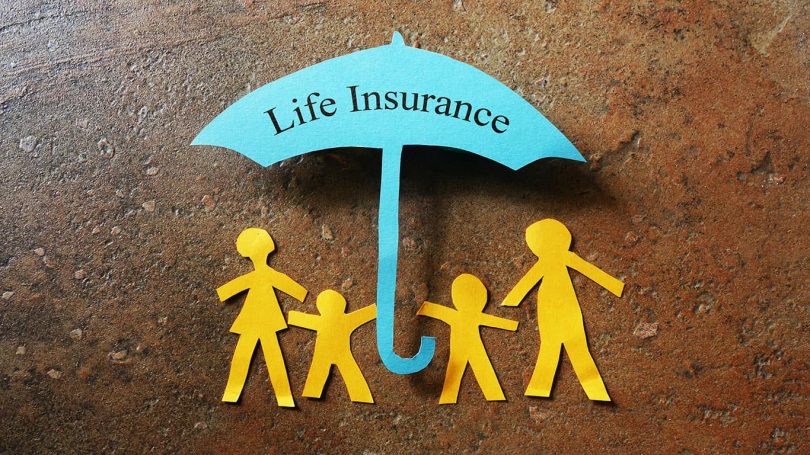 Paper family of four under a Life Insurance paper cutout umbrella