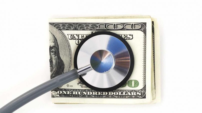 Stethoscope with hundred dollar bills on a white background. Financial check up.