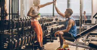 Excited couple at the gym celebrates savings on gym membership before workout
