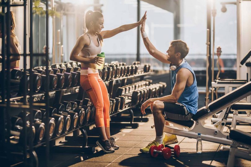 Excited couple at the gym celebrates savings on gym membership before workout