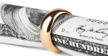 One hundred dollar bill in a gold wedding ring