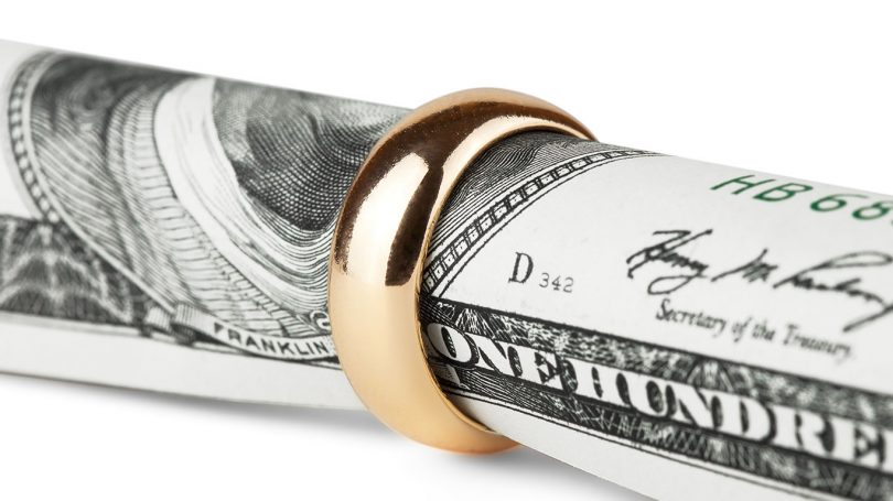One hundred dollar bill in a gold wedding ring