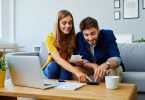 Young couple in their 20s sits at a table, managing their bills