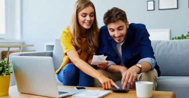 Young couple in their 20s sits at a table, managing their bills