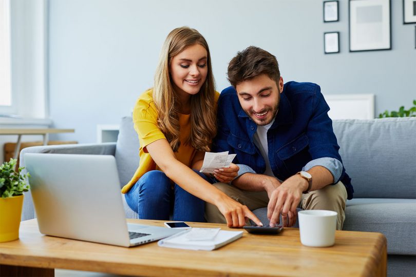 Young couple in their 20s sits at a table, managing their bills