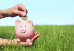 piggy bank being held in a green lawn