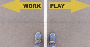 Work vs Play text on yellow arrows on asphalt ground