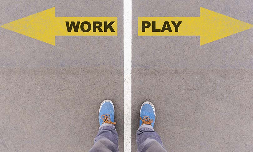 Work vs Play text on yellow arrows on asphalt ground